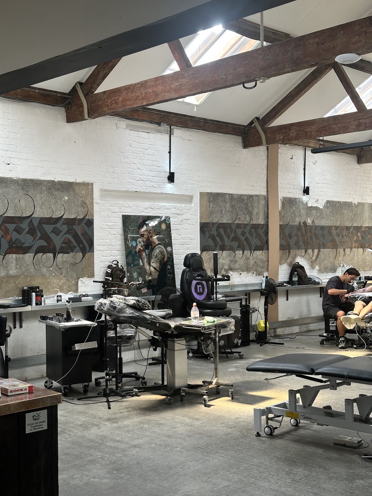 The studio floor at No Regrets: whitewashed brick, calligraphy panels and private tattoo stations