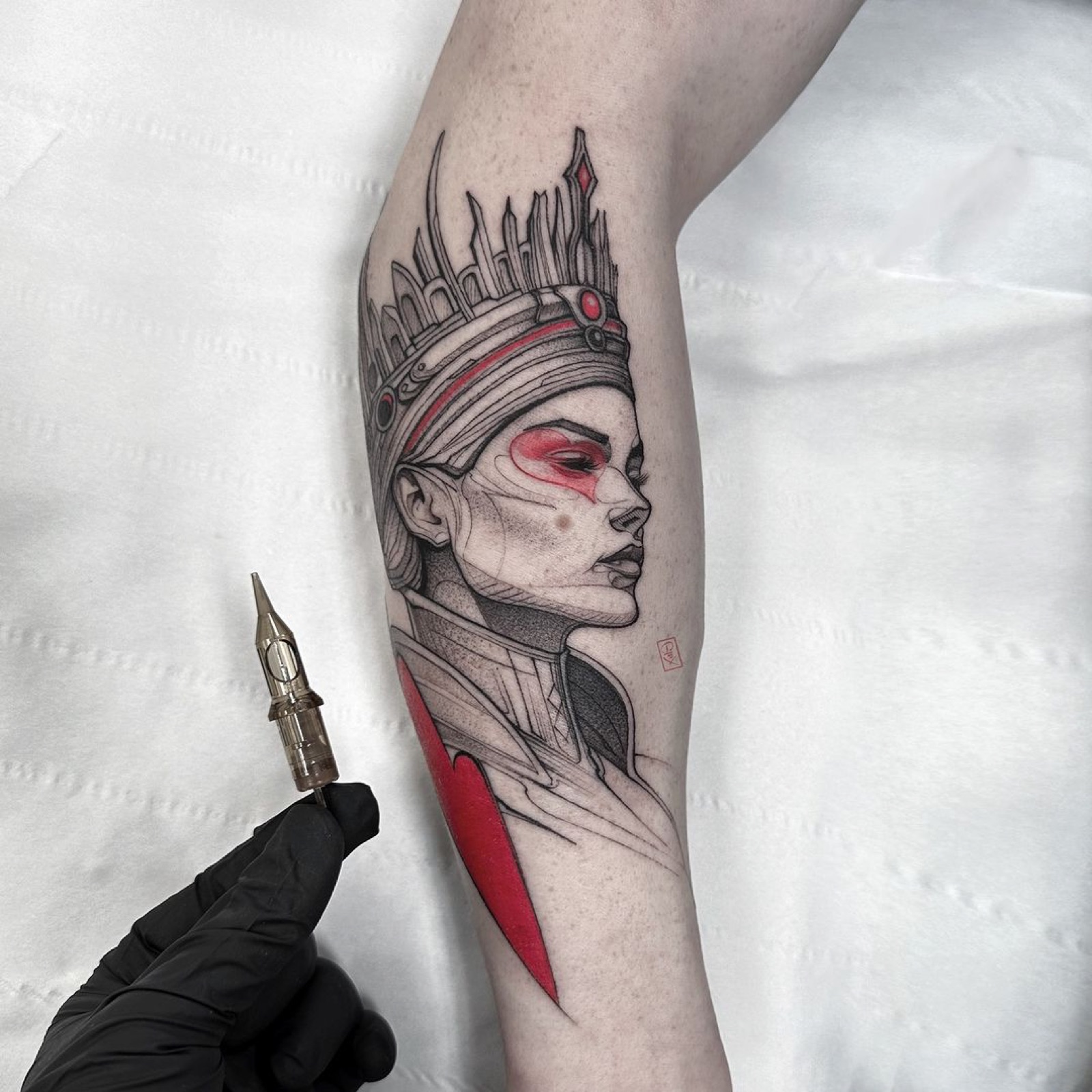 Fine line portrait of a crowned figure with red accents, being tattooed